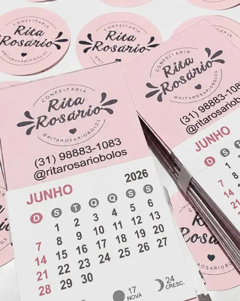 Calendários de geladeira cor-de-rosa com a logo da Confeitaria Rita Rosário e o telefone